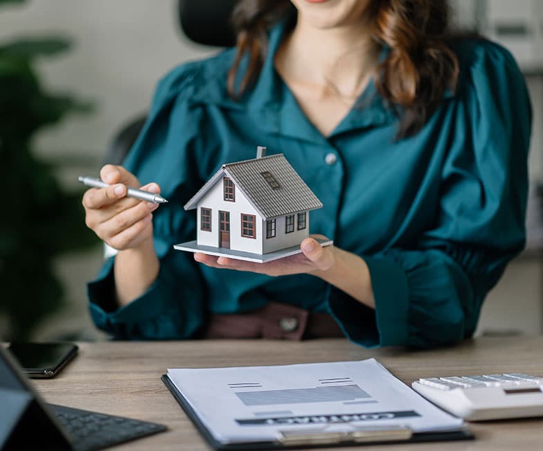 personne tenant un stylo et une maison miniature